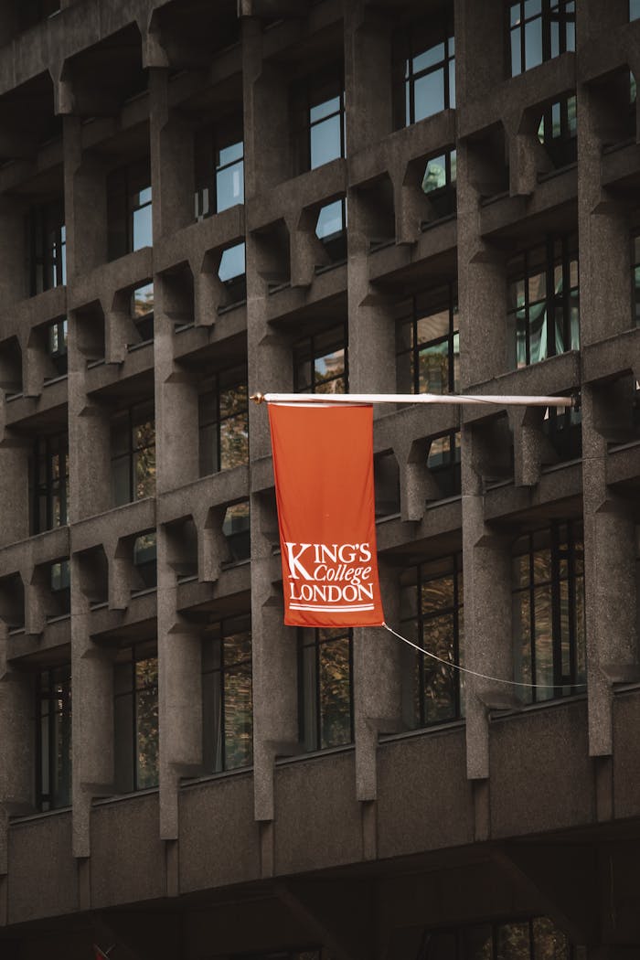 Close-up of King's College London flag on a modern architectural building facade.
